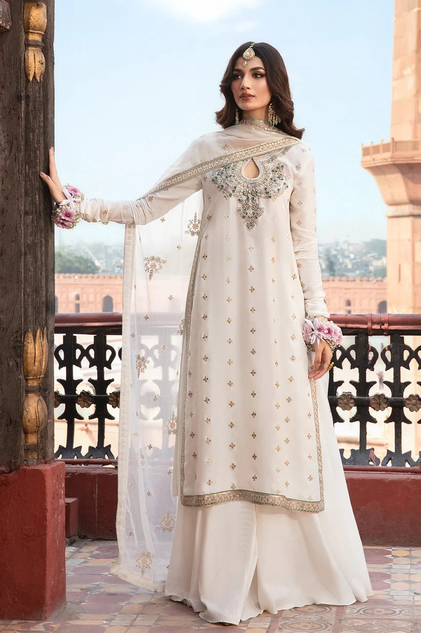 Woman in a traditional white outfit with intricate designs standing on a balcony with a scenic background.