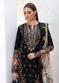 A woman models a black traditional embroidered kurta set with intricate gold, silver, and multicolor floral embroidery, paired with a beige printed dupatta, set against a white textured wall.