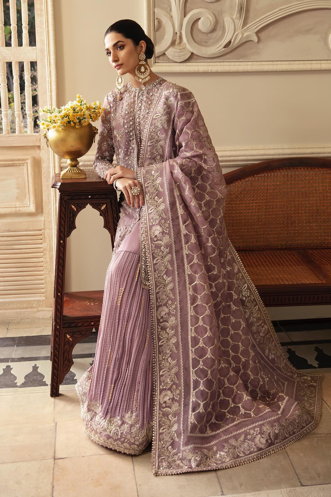 Woman in a traditional outfit standing in an elegant room with decorative elements.