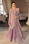 Woman in a pink embroidered traditional outfit standing in an elegant room.