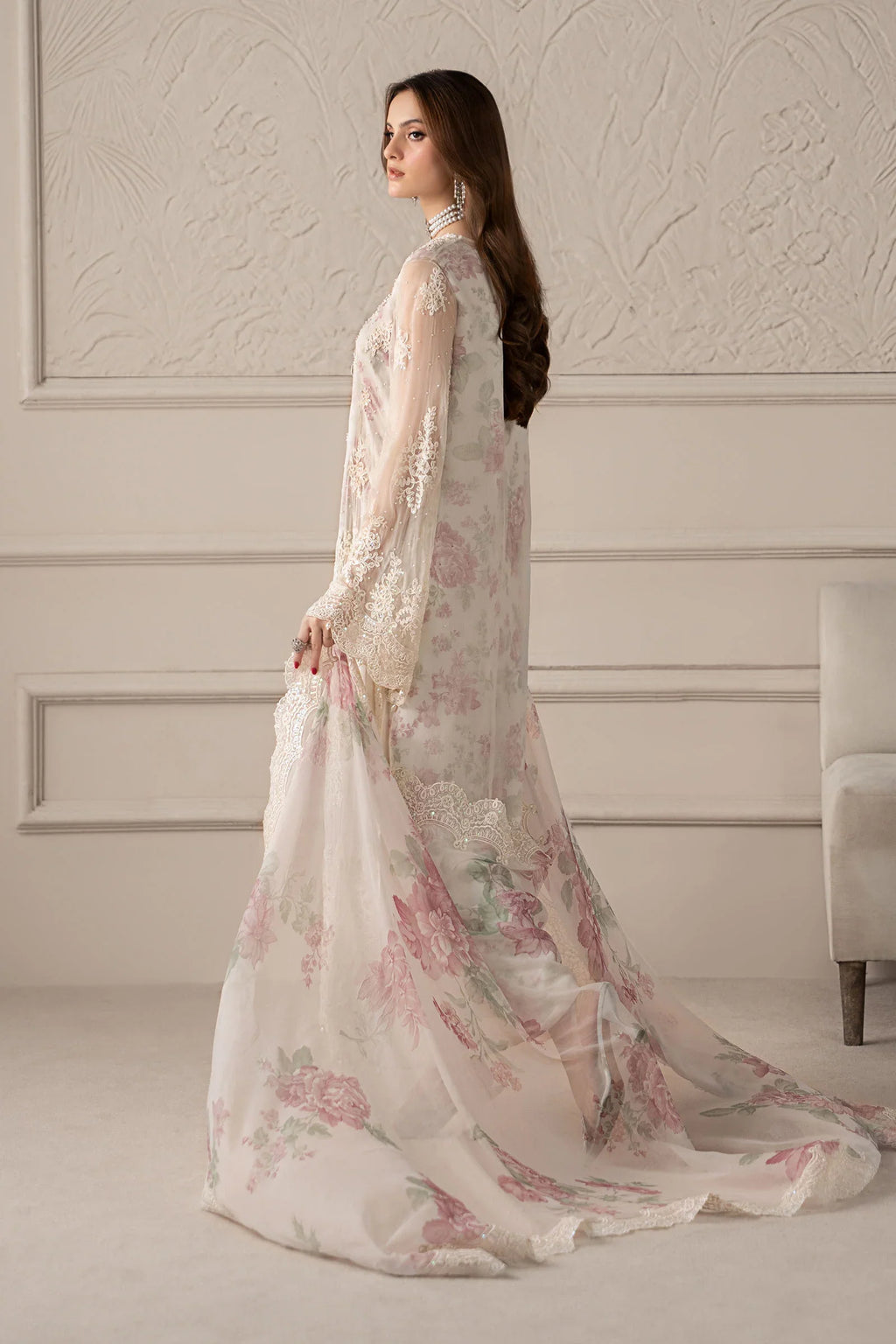 Woman wearing a floral dress in a room with decorative walls.