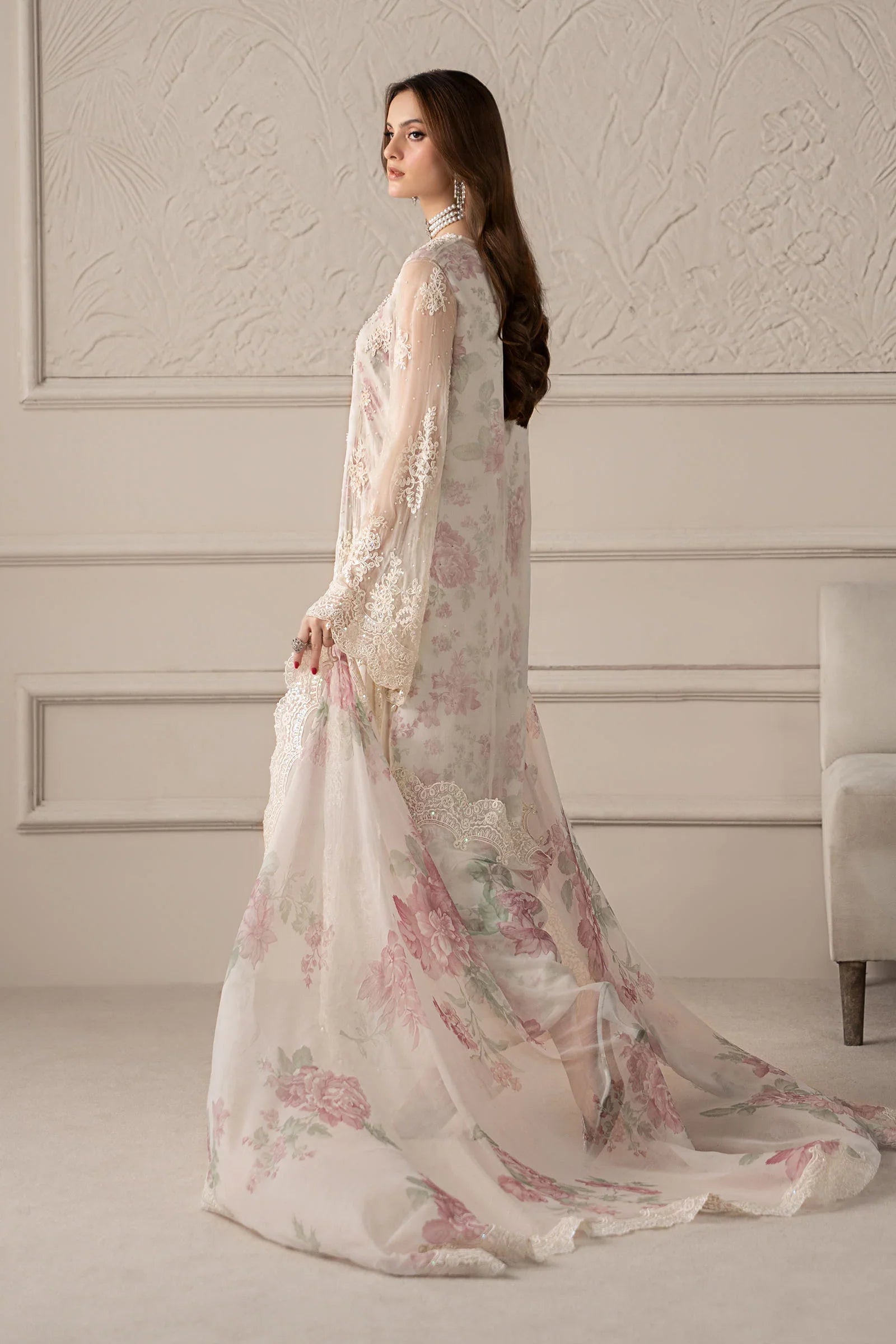 Woman wearing a floral dress in a room with decorative walls.