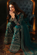 Woman in a traditional teal and gold outfit sitting on an ornate chair.